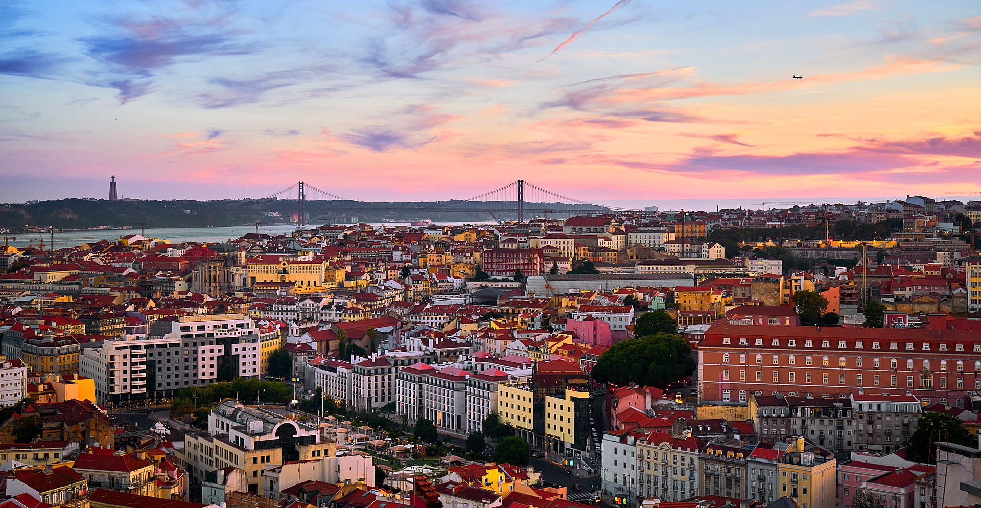 A photograph of Lisbon's landscape, with the 25 de Abril bridge and the river Tagus in the background.