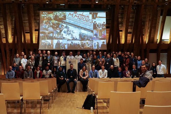 A photograph of the conference participants on the stage.